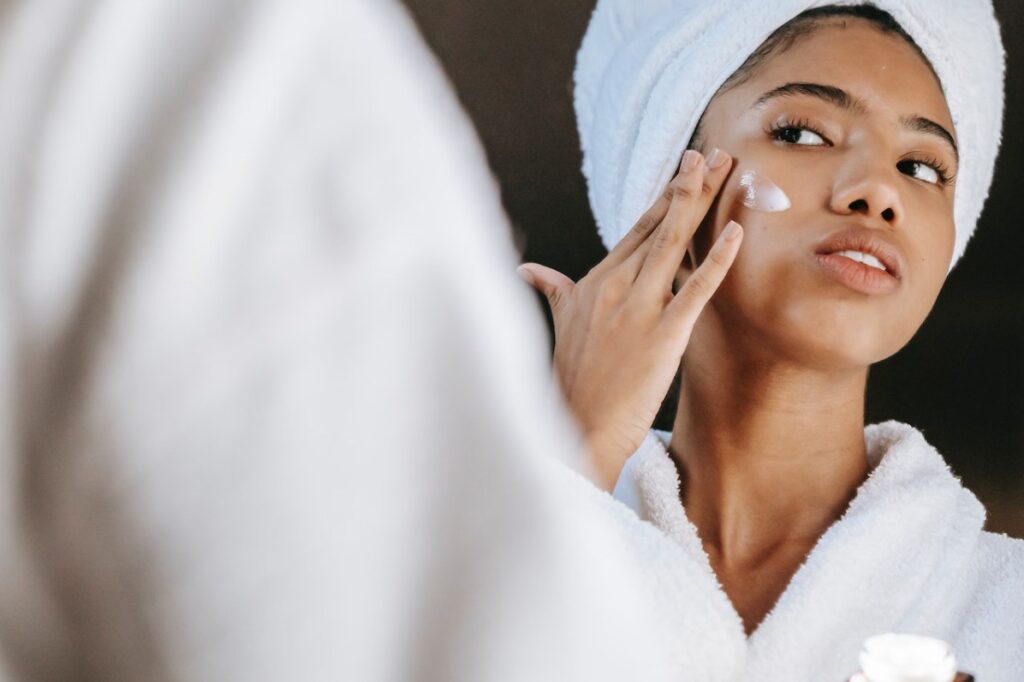 Women looking in the mirror applying sunscreen to her face.