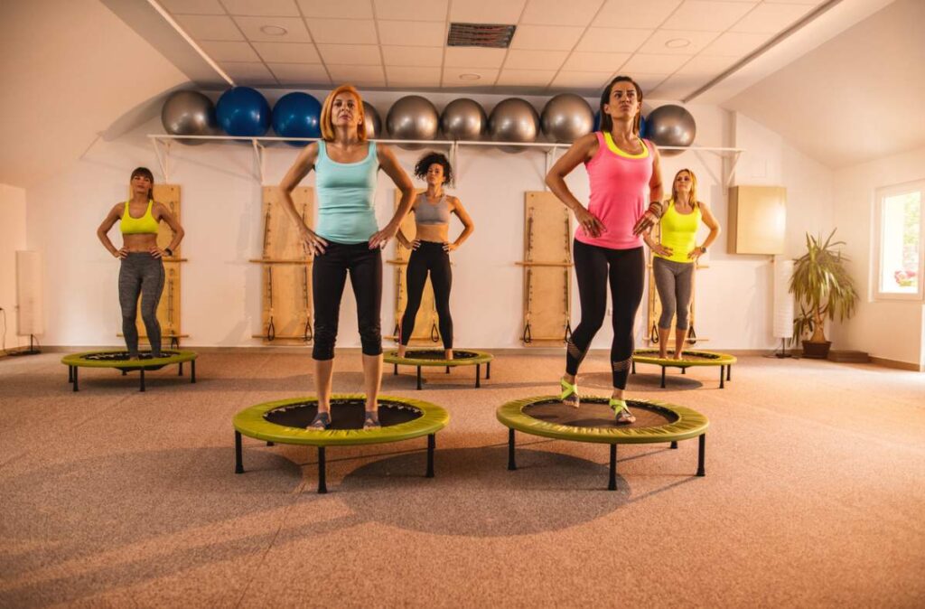 Group of women taking a rebounding class in a fitness studio.