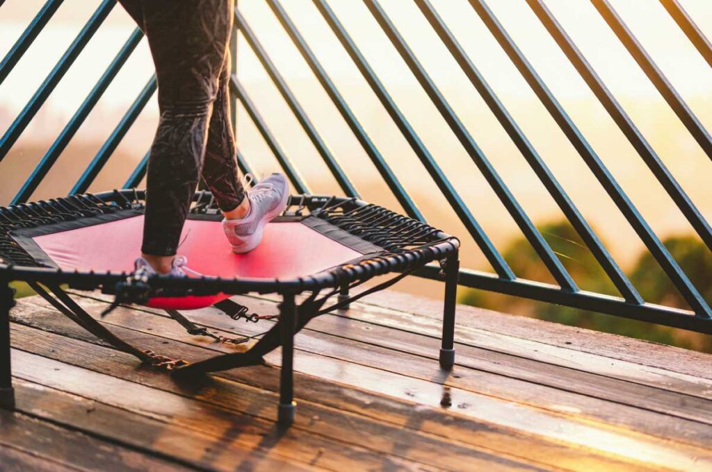 Picture from the waist down of someone on rebounder outside on a deck.